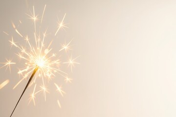 Obraz premium Sparkler burning with golden sparks on soft gradient background with clean space for text festive concept for New Year holiday celebration marketing and dynamic business visuals