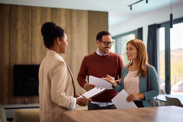Happy woman and her husband communicating with real estate agent during open house day.