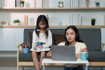 Sisterly Study Time. Young woman working on a laptop while her sister takes notes.