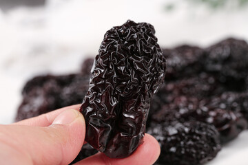 Hand Holding Dark Dried Jujube Fruit with Wrinkled Black Texture