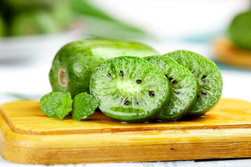 Fresh Kiwi Berry Slices with Mint on Wooden Board - Healthy Organic Fruit Background