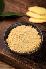 Dried Ginger Powder in Bowl with Fresh Ginger Slices on Wooden Background - Natural Spice Ingredient