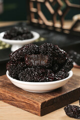 Large Black Dried Jujubes from Shaanxi Province China in White Bowl on Wooden Board