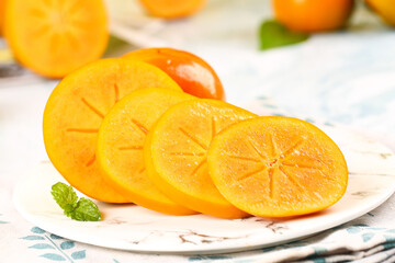 Fresh Sliced Persimmon Fruit with Star Pattern on White Plate with Mint Garnish