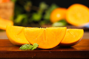 Fresh Persimmon Slices with Mint on Wooden Board - Healthy Autumn Fruit Photography