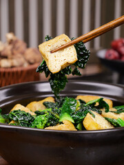 Fried Tofu Puffs with Greens in Hot Pot - Traditional Asian Cuisine with Chopsticks