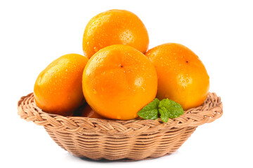 Fresh oranges in wicker basket with mint leaves isolated on white background