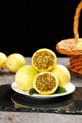 Golden Passion Fruit Cut in Half Showing Seeds and Pulp on Plate with Wicker Basket