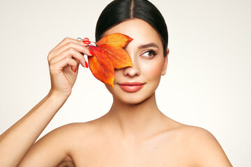 Portrait of beautiful young woman with autumn leafs. Healthy clean fresh skin natural make up...