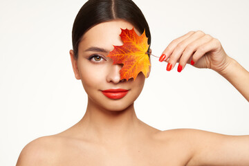 Portrait of beautiful young woman with autumn leafs. Healthy clean fresh skin natural make up beauty eyes and red nails