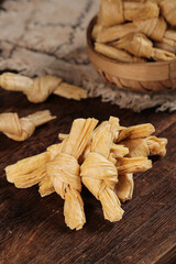 Handmade dried bean curd skin knots on wooden table - traditional Asian tofu food ingredient