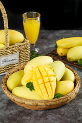 Fresh Vietnamese Jade Mangoes in Wicker Basket with Juice Glass and Diced Fruit on Rustic Wood Background