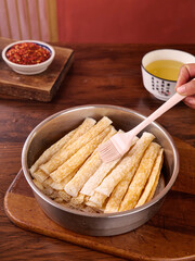 Brushing Oil on Handmade Dry Pasta Rolls with Chili Flakes for Traditional Italian Cooking