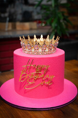 The cake is bright pink with a crown on top and the words: Happy Birthday Eva!