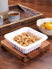 Japanese Natto Fermented Soybeans Traditional Breakfast with Tea and Raw Egg on Wooden Table