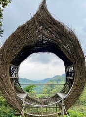 Bird's nest structure at a tourist attraction as a unique photo spot or observation deck, made from woven branches with the scenic backdrop for visitors to take pictures