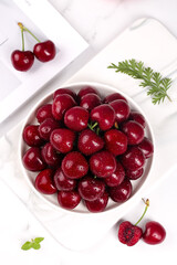 Fresh Red Cherries in Bowl on Marble Background with Green Herbs - Healthy Summer Fruit