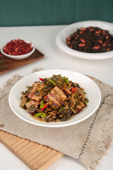 Traditional Chinese Stir-Fried Bacon with Dried Vegetables and Red Peppers on White Plate