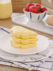 Traditional lotus shaped golden pastries stacked on plate with fresh ingredients kitchen scene