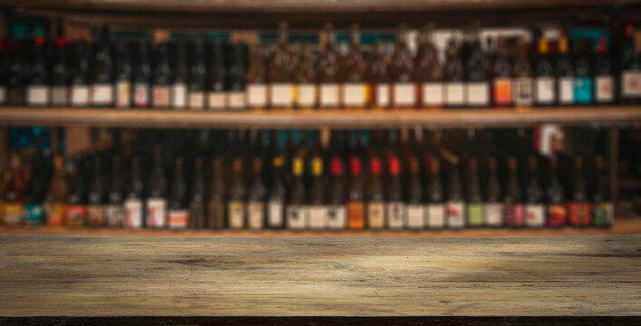 Wine wooden table background. Blurred wine shop with bottles on the counter. 