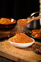 Spicy Red Chili Powder Seasoning Being Sprinkled from Wooden Spoon - Asian Cooking Spices
