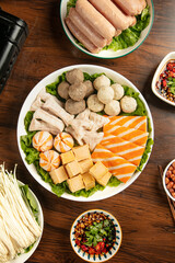 Hot pot ingredients with meatballs mushrooms and vegetables prepared for Asian cooking on wooden table