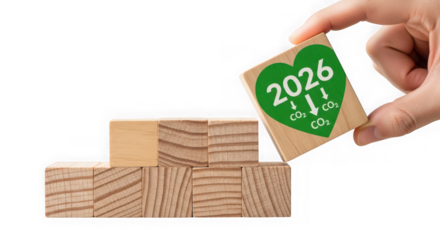 Hand placing a wooden block with a green heart symbol and 2026 with co2 reduction arrows, isolated on transparent background