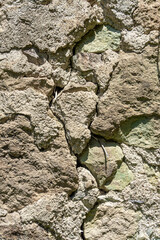 The masonry of an antique wall made of rough dark stones of different sizes, bonded with light mortar