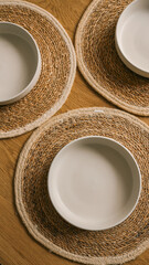 Overhead shot of plates on woven placemats on a wooden table.