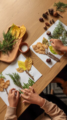 Children creating art with autumn leaves and natural materials on a wooden table.