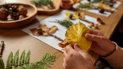 Child holding a yellow leaf during an autumn craft activity
