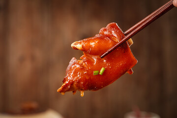 Glazed Pork Trotters with Soy Sauce - Traditional Asian Cuisine Delicacy Held with Chopsticks