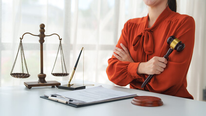 Lawyer holding gavel with scales of justice and documents on desk