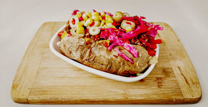 Baked kumpir potato stuffed with the cheese, sausage, olives, peppers and corn. Turkish baked potato with butter, cheese, chicken, barbecue sauce and spices. This kumpir is traditional turkish food .