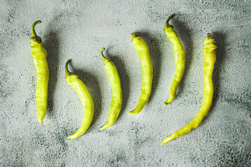 Flat lay of fresh tsitsak peppers on a textured grey background. Minimalist composition, vibrant green color, traditional spicy ingredient in Georgian and Caucasian cuisine