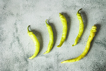 Flat lay of fresh tsitsak peppers on a textured grey background. Minimalist composition, vibrant green color, traditional spicy ingredient in Georgian and Caucasian cuisine