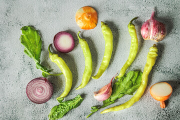 Top view of fresh red and white onions, tsitsak chili peppers, and greens. Traditional Georgian vegetables, seasonal ingredients, bright and spicy food mood