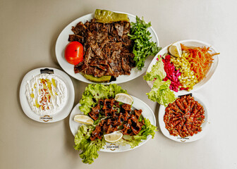 Delicious meat kebab with fresh vegetable salad served with variety of Turkish dishes and appetizers. Top view of assorted Turkish food and meze, tasty and healthy Mediterranean cuisine. Top view.
