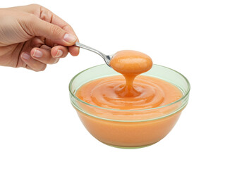 Isolated fruit spread on spoon dripping into bowl filled with delicious peach jam, marmalade