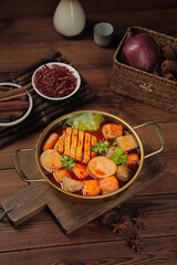 Traditional Asian hot pot with tofu and vegetables in brass cooking pot on rustic wooden table