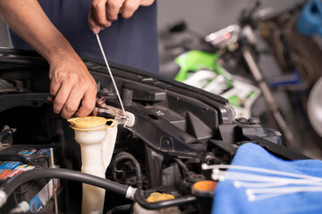 Asian man uses cable ties as temporary replacement nuts for basic car maintenance.