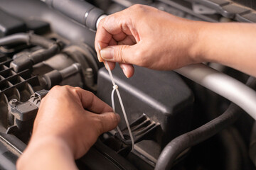 Asian man uses cable ties as temporary replacement nuts for basic car maintenance.