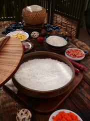 Traditional Asian fragrant rice cooking with bamboo steamer and fresh ingredients on wooden table