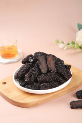 Xinjiang Black Jujube Dried Dates on Wooden Board with Tea - Healthy Chinese Snack Food Photography