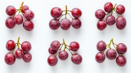 Six bunches of fresh red grapes arranged symmetrically on a white surface