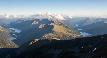 Panoramic view of majestic mountain ranges with serene lakes reflecting the sky under a clear blue sky with scattered clouds.