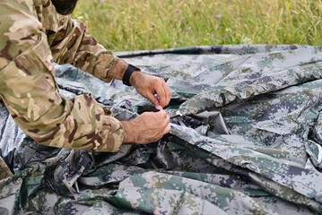 Close up of man setting up camping tent with hands
