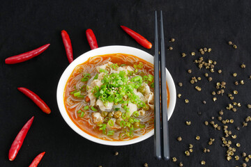 Close-up hot and sour rice noodle soup on black background, top view