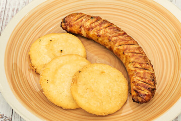 Grilled Venezuelan sausages with caramelized onions and roasted peppers, served on crispy arepas with guacamole sauce