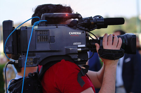 Operador de c&aacute;mara de televisi&oacute;n filmando en exteriores un programa en directo TV
